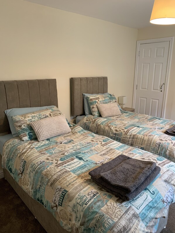 Ein Schlafzimmer mit zwei Betten, jedes mit einem Kopfteil und einer gemusterten Bettdecke.
