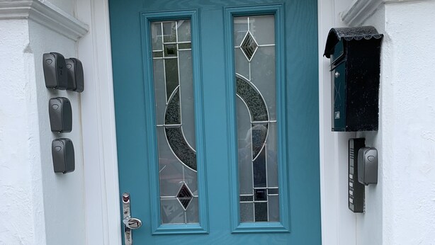 Una puerta doble color turquesa con un panel de vidrio, una ranura para correo y un buzón a la derecha.