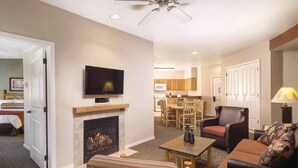 A hotel room with a fireplace, a television, a dining area with a table and chairs, and a sofa.