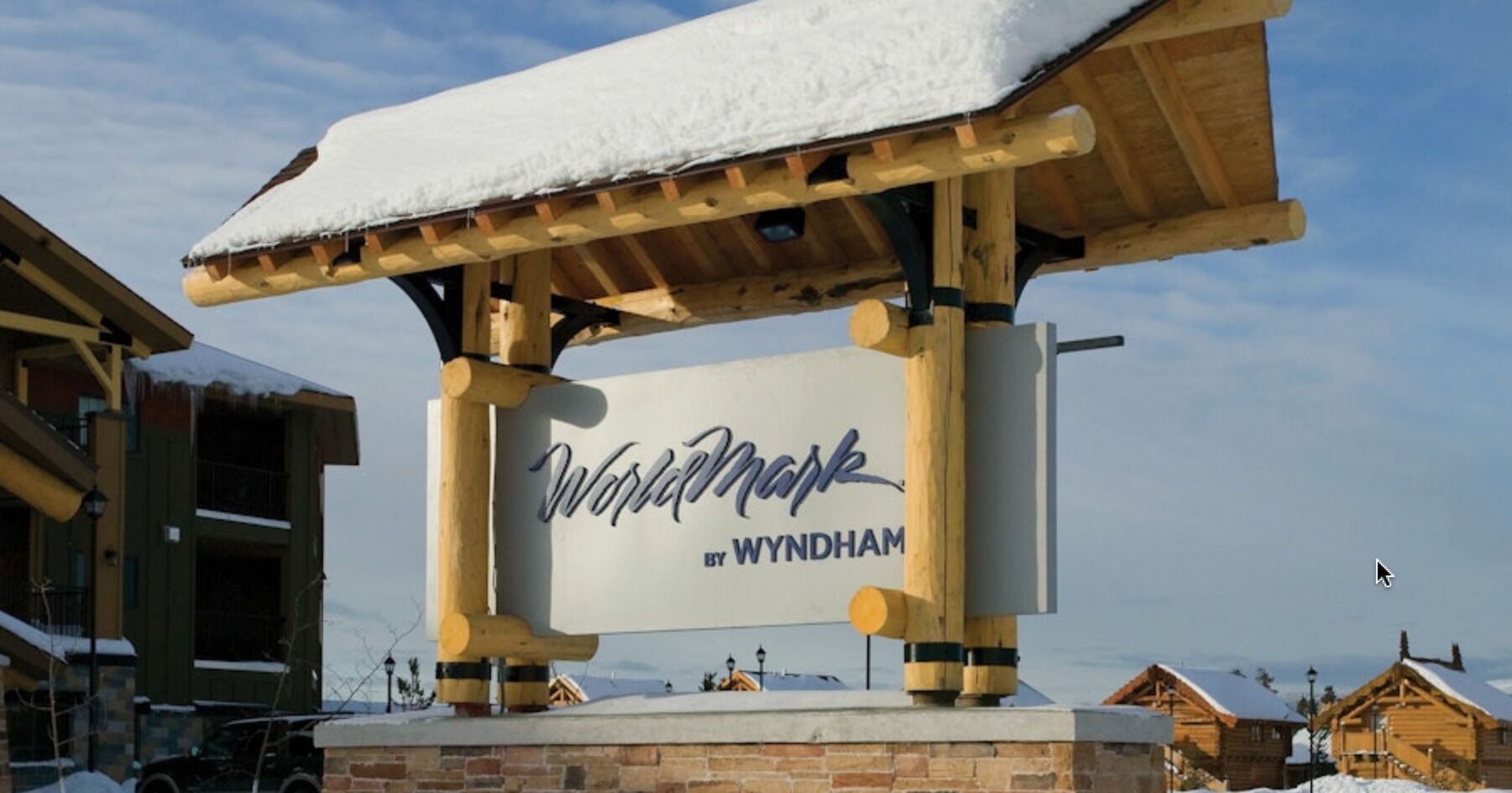 Puinen kyltti, jossa lukee ”Wynhammark” ja ”BY WYNDHAM”, ja joka on kiinnitetty puiseen tukirakenteeseen.