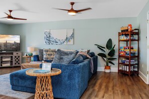 Een woonkamer met een blauwe bank, een houten boekenkast en plafondventilatoren.
