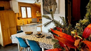 A cozy kitchen with wooden cabinets, a dining table with blue chairs, and a framed picture of a wolf on the wall.
