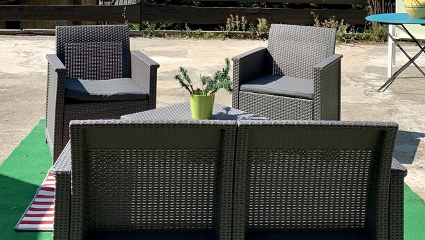 Wicker chairs with a view of mountains and a building with a chimney.