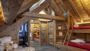 A cozy attic bedroom with wooden beams, a loft bed, and a small play area with stuffed animals. - Chalet, wifi, 150m from ski slopes, sauna, terrace, fireplace or stove, tv, 260m², Les 2 Alpes (Les Deux Alpes)