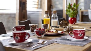 A breakfast table with red cups, a bowl of berries, a glass of orange juice, and a bottle of milk. - Chalet, wifi, 150m from ski slopes, sauna, terrace, fireplace or stove, tv, 260m², Les 2 Alpes (Les Deux Alpes)