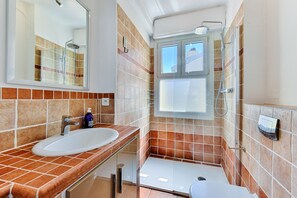 A bathroom with a white sink, a shower, and a toilet. - Happyfew La terrasse de Rossini (Nice)