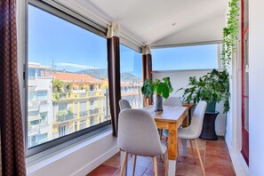 A balcony with a dining table, chairs, and potted plants. - Happyfew La terrasse de Rossini (Nice)