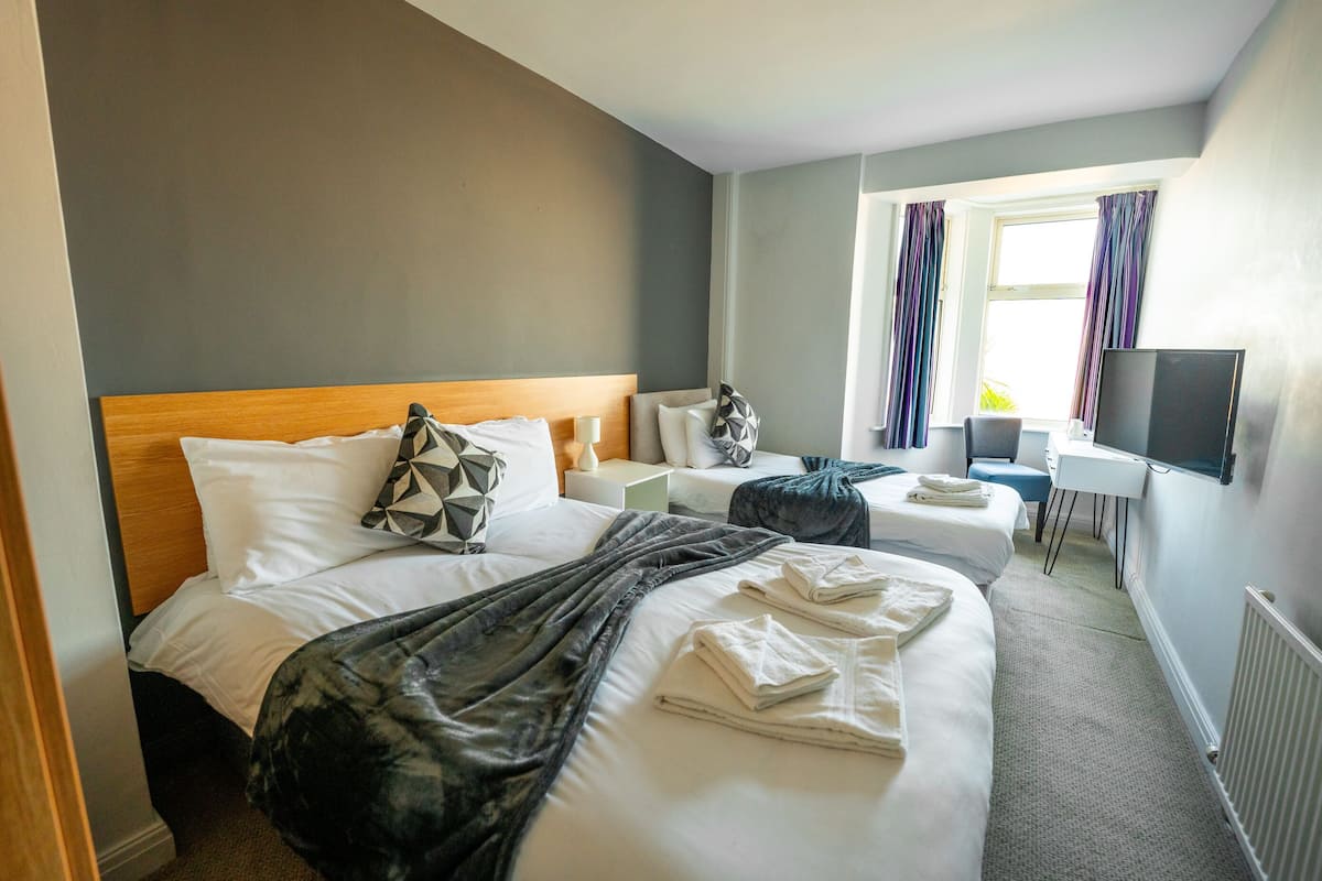 Habitación de hotel con una cama grande, un escritorio, un televisor y una ventana con cortinas.