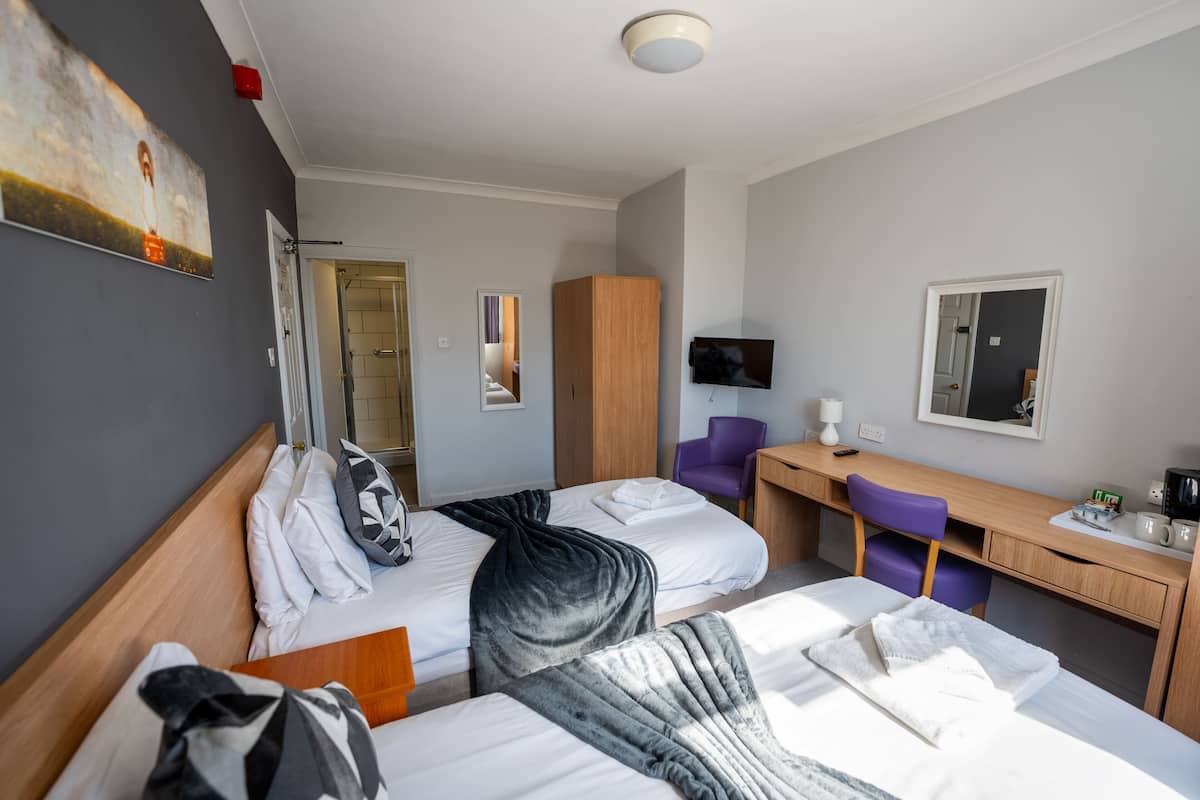 Habitación de hotel con dos camas, un escritorio, una silla, un televisor y un armario.