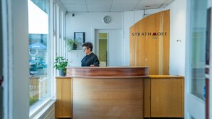 A reception area with a wooden reception desk, a clock on the wall, and a sign that reads "STRATHMORE".