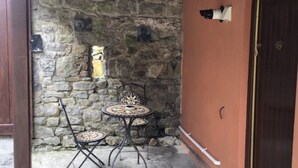 Eine Steinsäule mit einem kleinen Fenster, einem Tisch mit Stühlen und einer Tür.