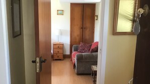 Ein Flur, der zu einem Schlafzimmer mit Bett, Kommode und Kleiderschrank führt.