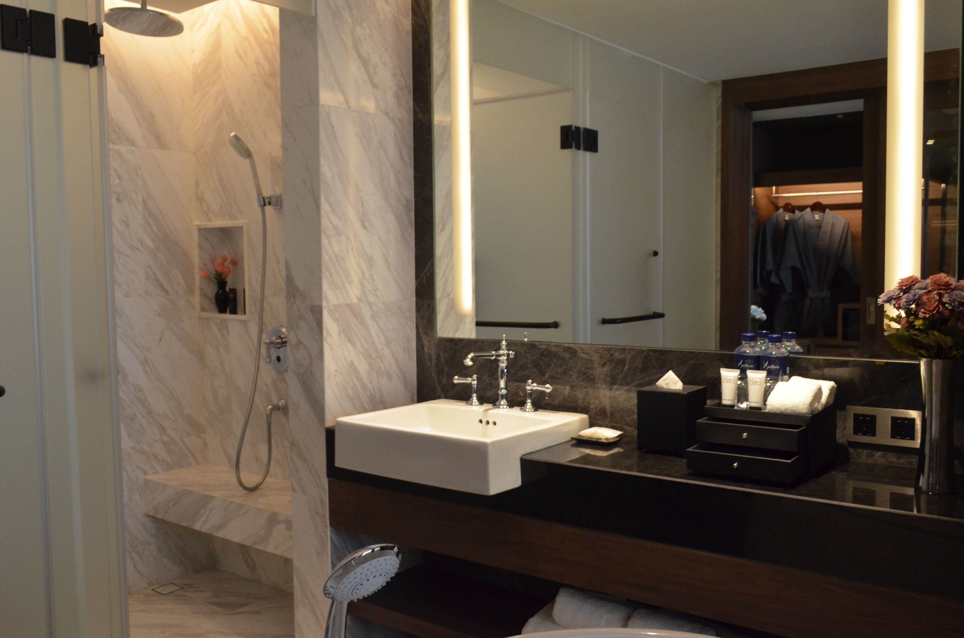 Une salle de bain moderne avec un lavabo en marbre, un grand miroir et un espace douche.