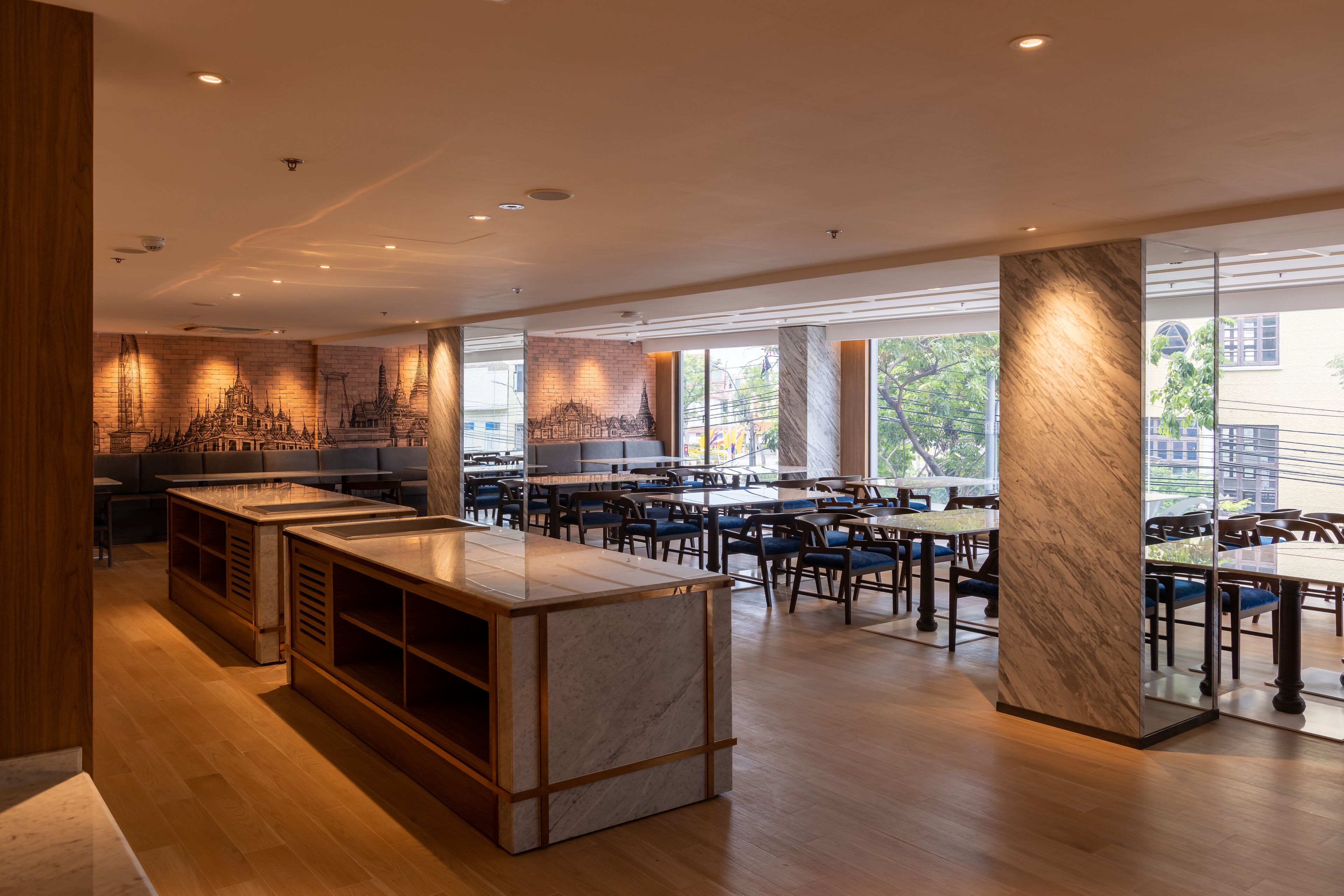 A modern restaurant with a marble bar, wooden flooring, and large windows offering views of the city.