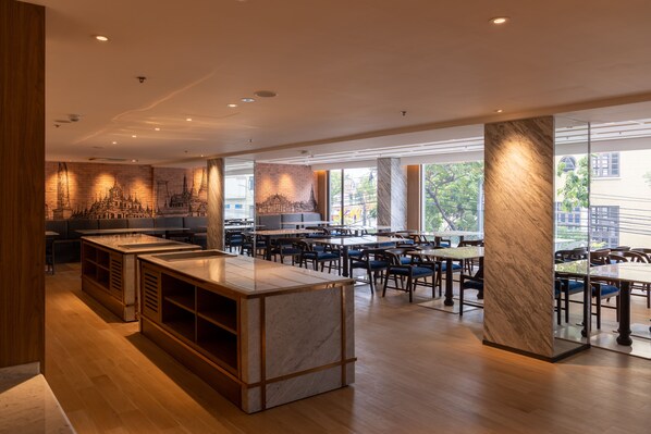 Un restaurant moderne doté d’un bar en marbre, de parquets en bois et de grandes fenêtres offrant une vue sur la ville.