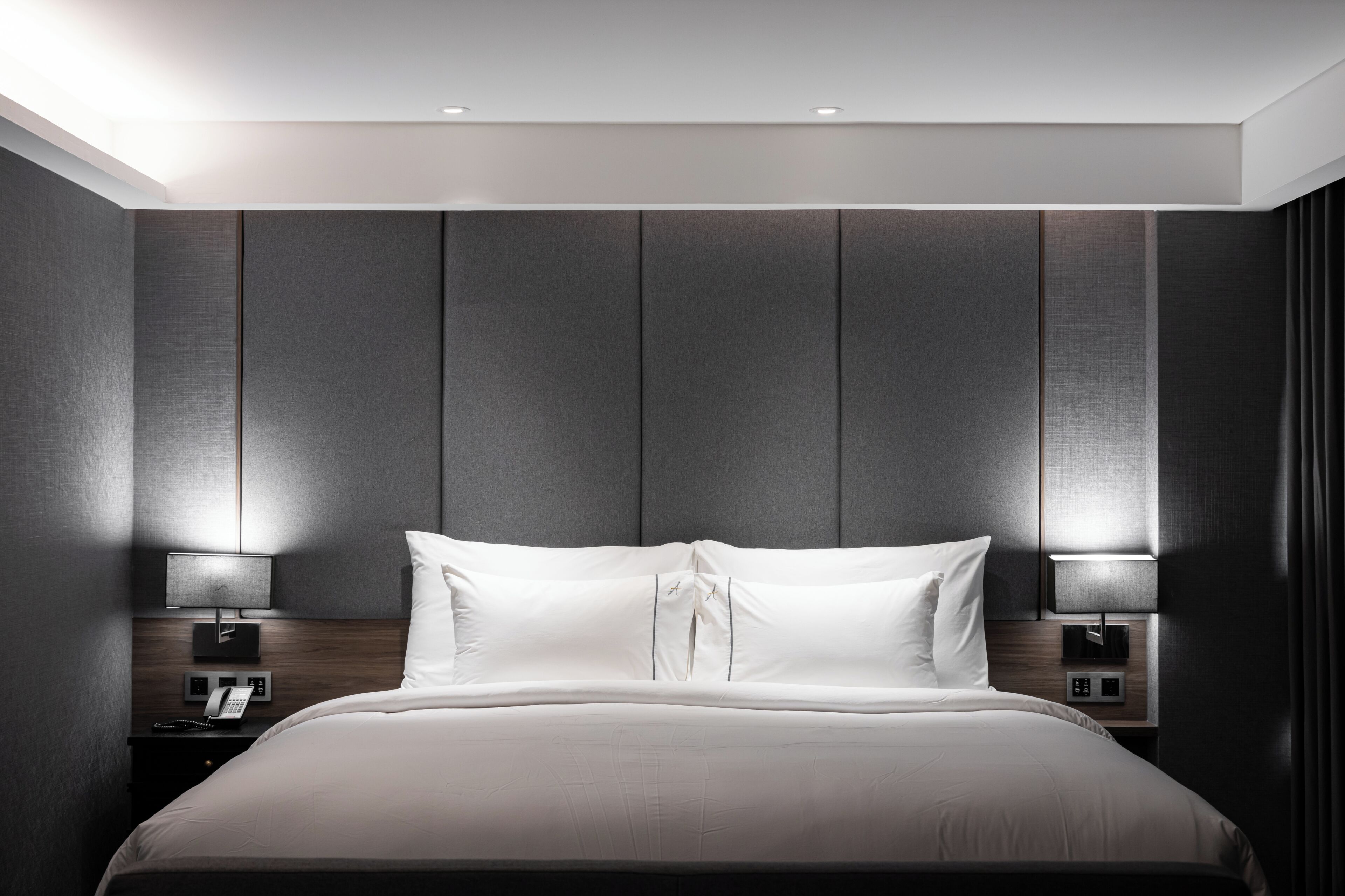 Et moderne hotelværelse med en stor seng, to sengeborde med lamper og en indbygget telefon.
