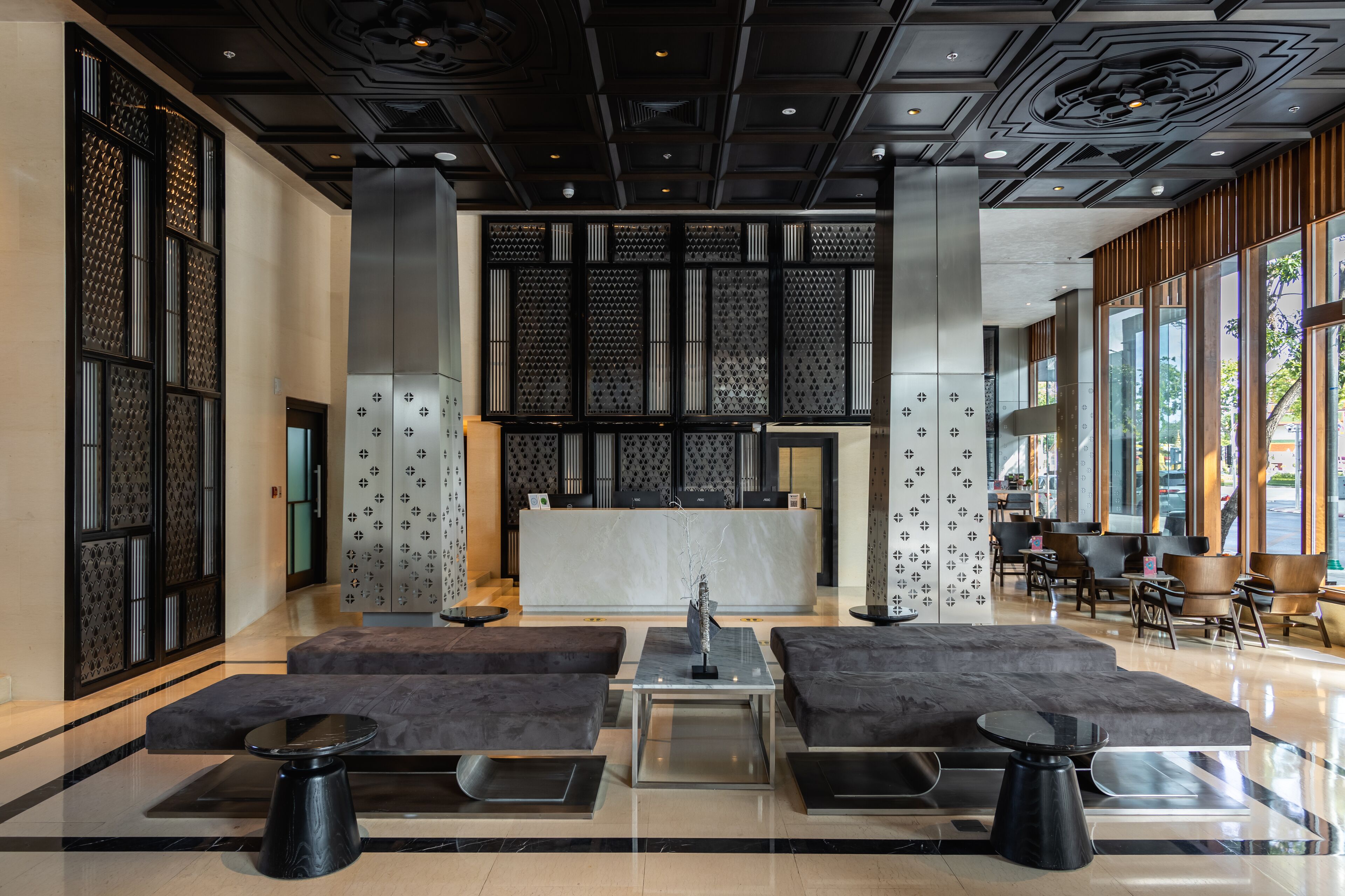 A modern lobby with a reception desk, seating areas, and large windows.