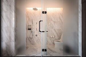 Un baño moderno con cabina de ducha de vidrio, baldosas de mármol y un inodoro.