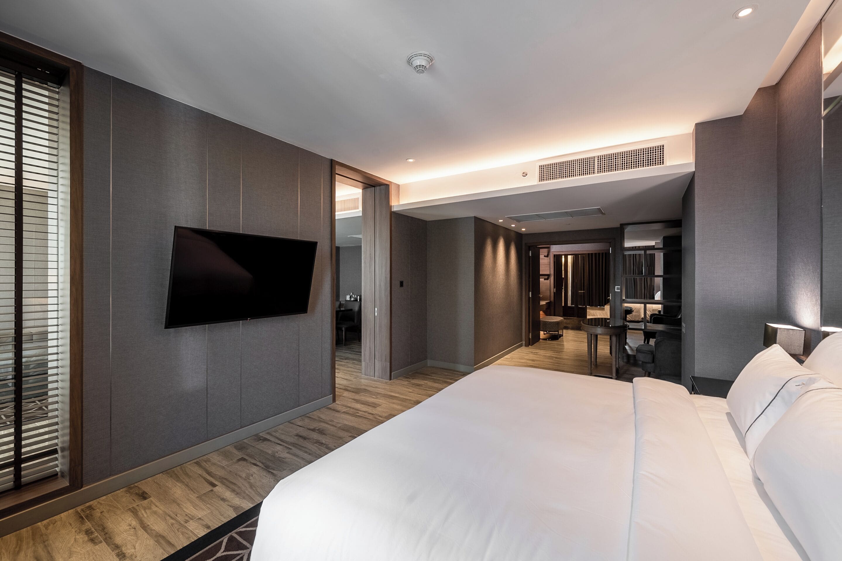 Een moderne hotelkamer met een groot bed, een flatscreen televisie aan de muur en een inloopkast.