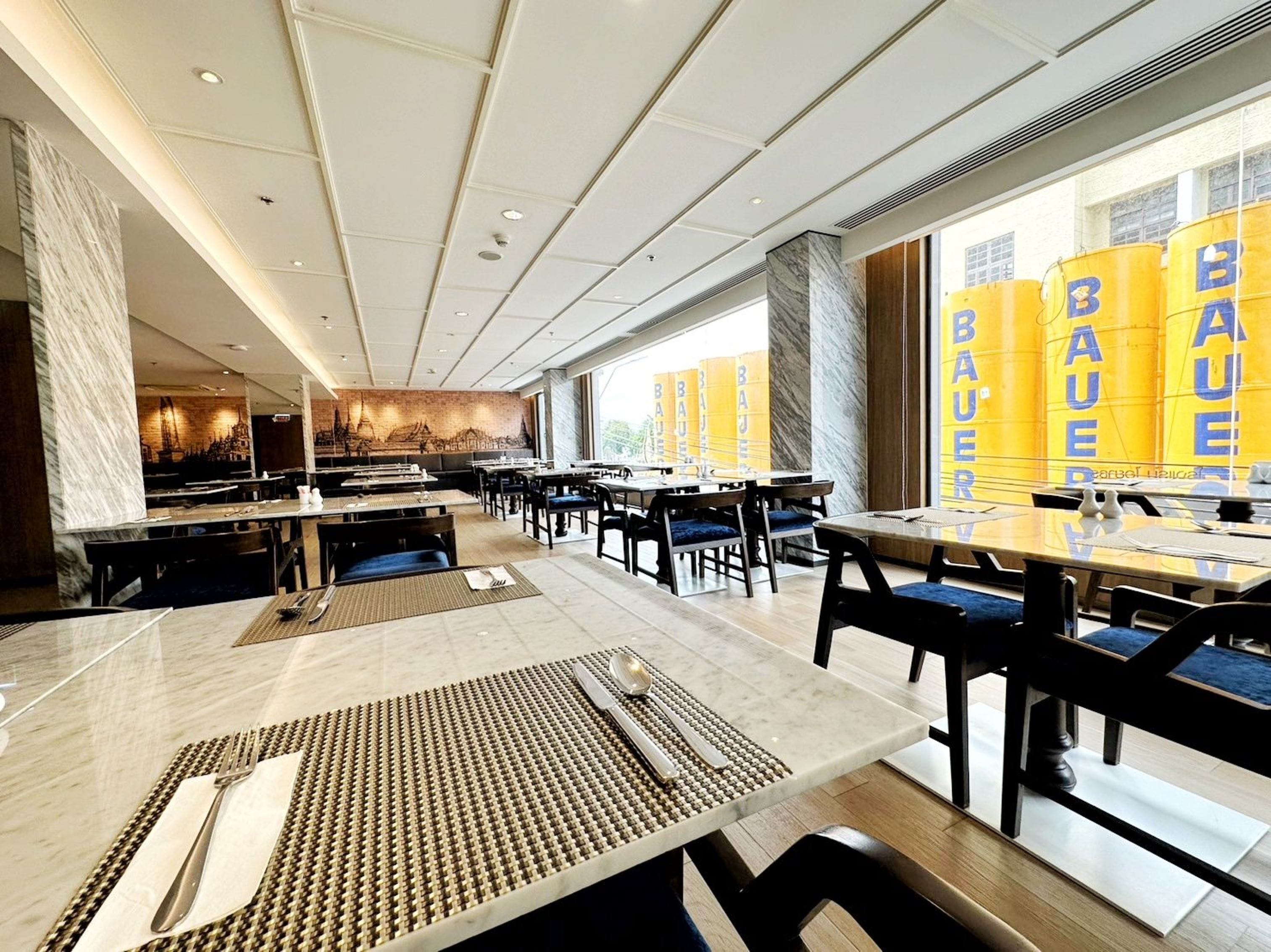 A modern restaurant with marble flooring, wooden tables, and chairs.