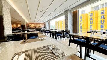 A modern restaurant with marble flooring, wooden tables, and chairs.