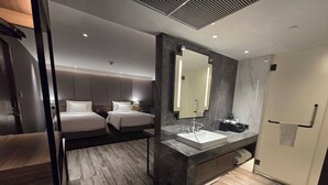 A modern hotel room with a large bed, a separate bed, a marble bathroom with a sink, and a large mirror.