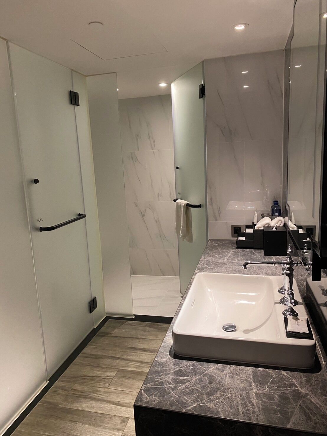 A modern bathroom with a large mirror, a walk-in shower, and a marble countertop.