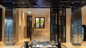 A modern lobby with a staircase, seating area, and decorative panels.