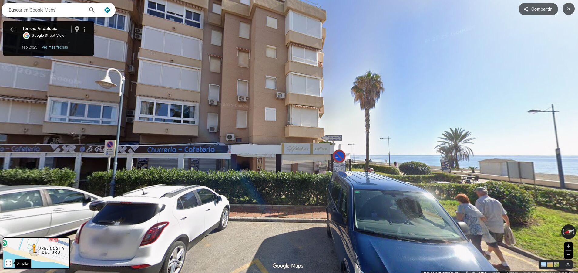 A multi-story building with balconies, a cafe, and a view of the sea.