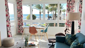 Une pièce avec vue sur la plage, une table à manger avec des chaises, un canapé et une lampe.