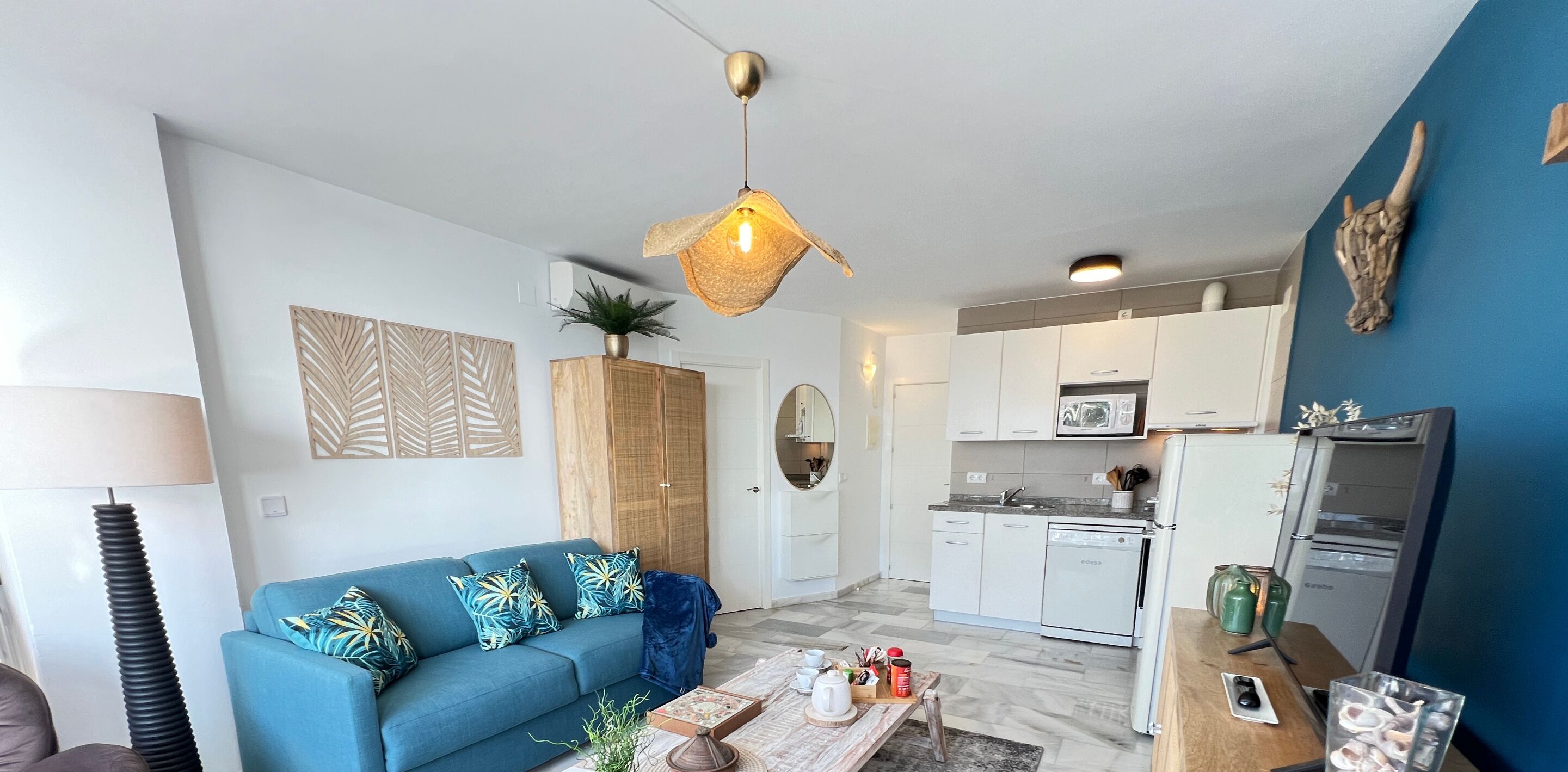 Un salon moderne avec un canapé bleu, une table basse en bois et un luminaire suspendu.