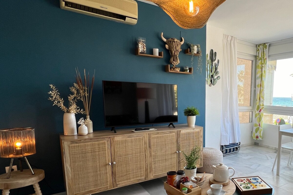 Uma sala de estar com televisão, um armário de madeira e uma área de jantar com mesa e cadeiras.