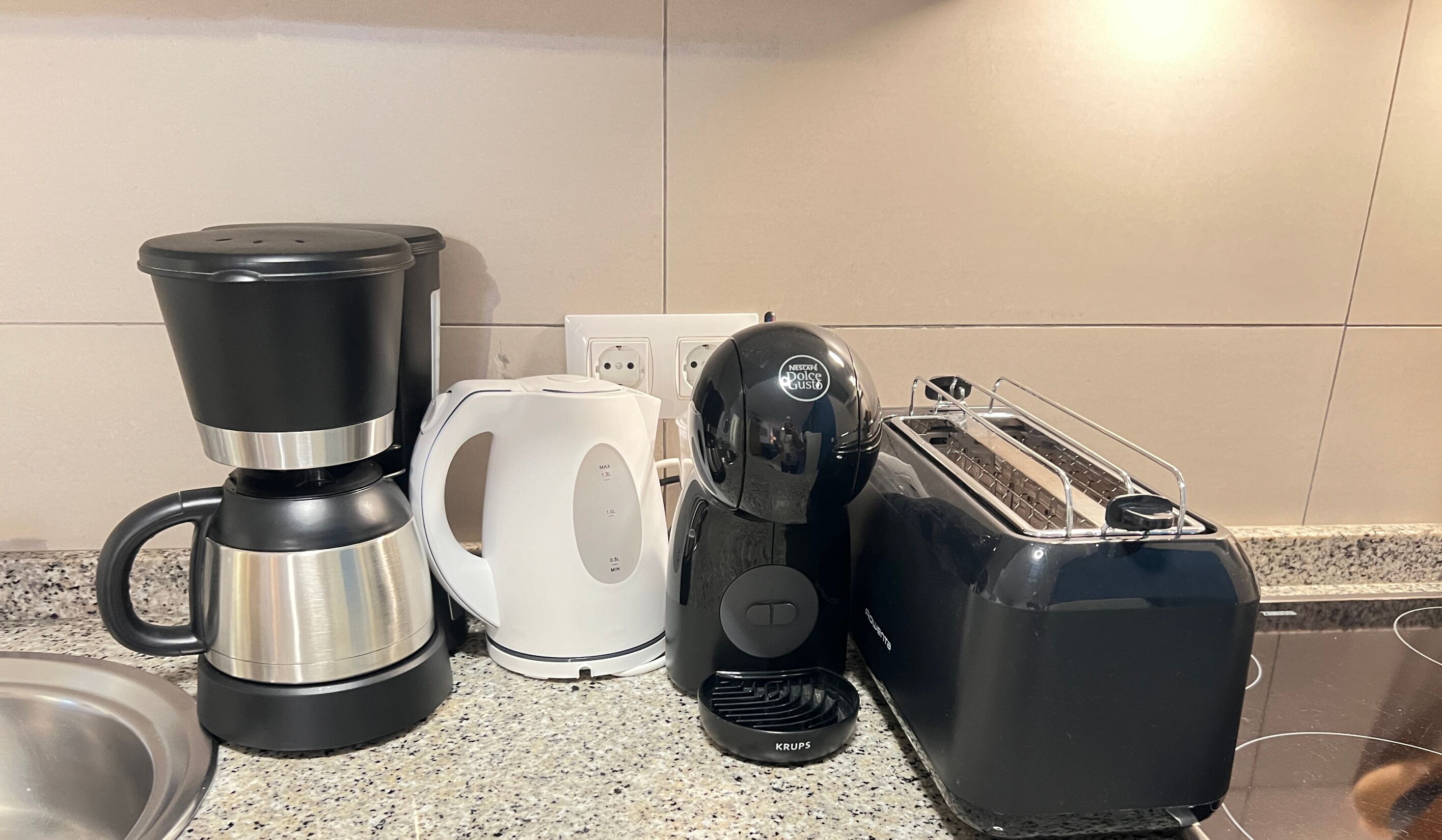 A kitchen with a coffee maker, a toaster, and a kettle on the counter.