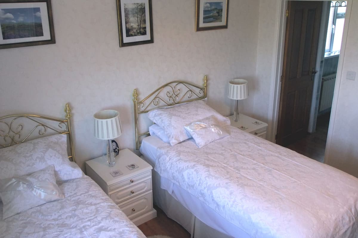 A bedroom with two single beds, each with a nightstand, a lamp, and a framed picture on the wall.