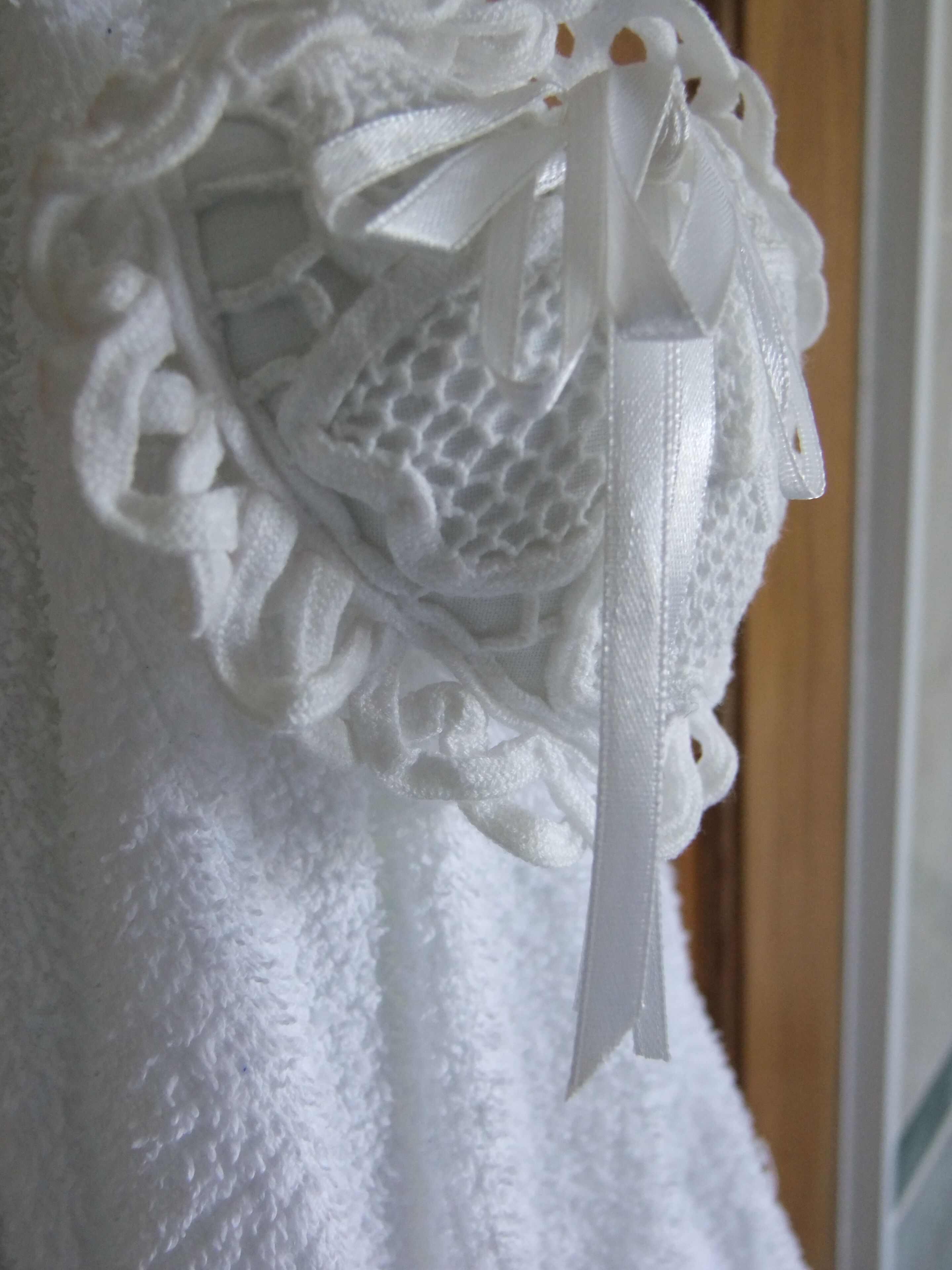 A white textured fabric with a lace pattern and a ribbon detail.