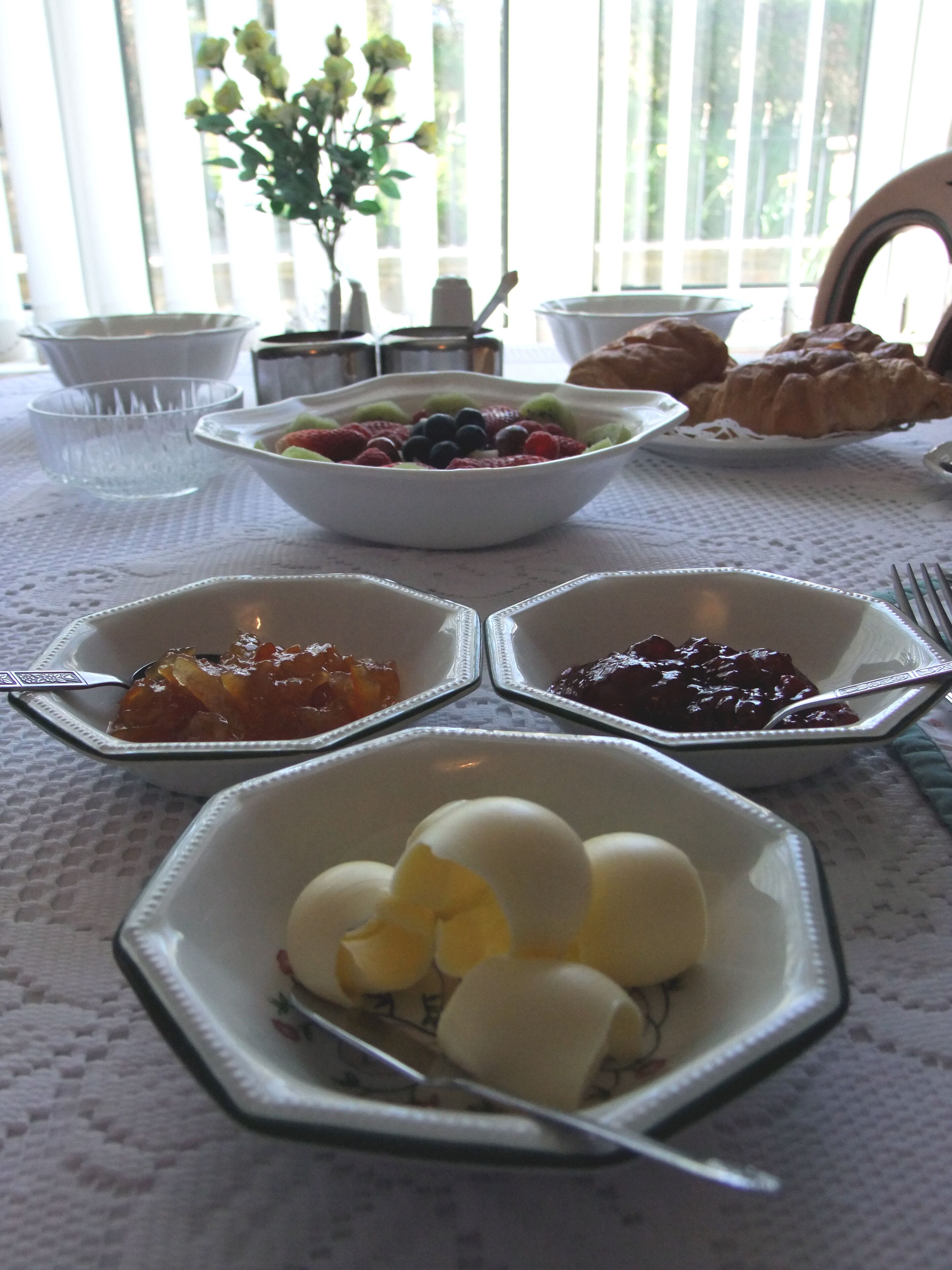 Un desayuno con una variedad de platillos, incluyendo huevos, bayas y pasteles sobre una mesa.