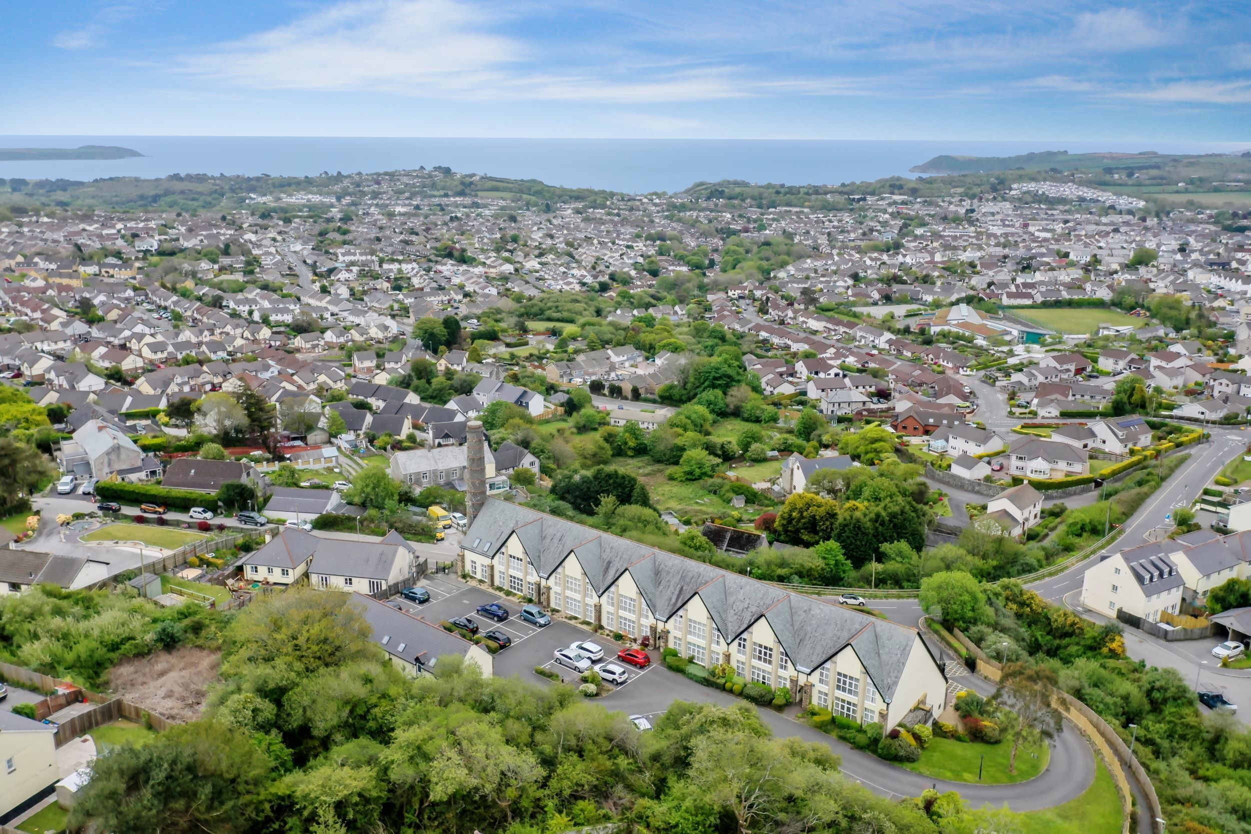A residential area with a row of houses, a parking lot, and a body of water in the background.