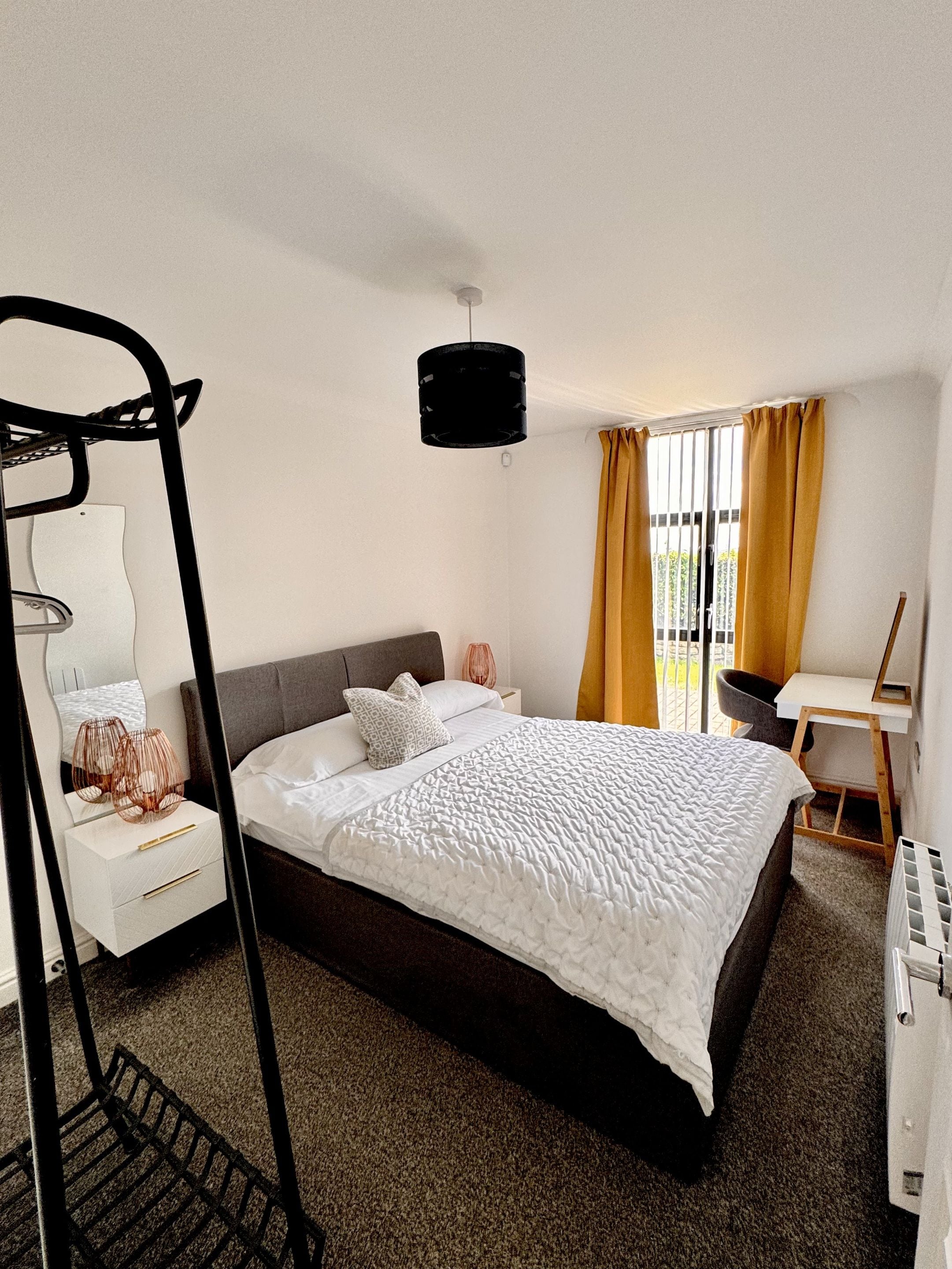 Un dormitorio moderno con una cama grande, un escritorio y una silla.