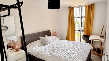 Un dormitorio moderno con una cama grande, un escritorio y una silla.