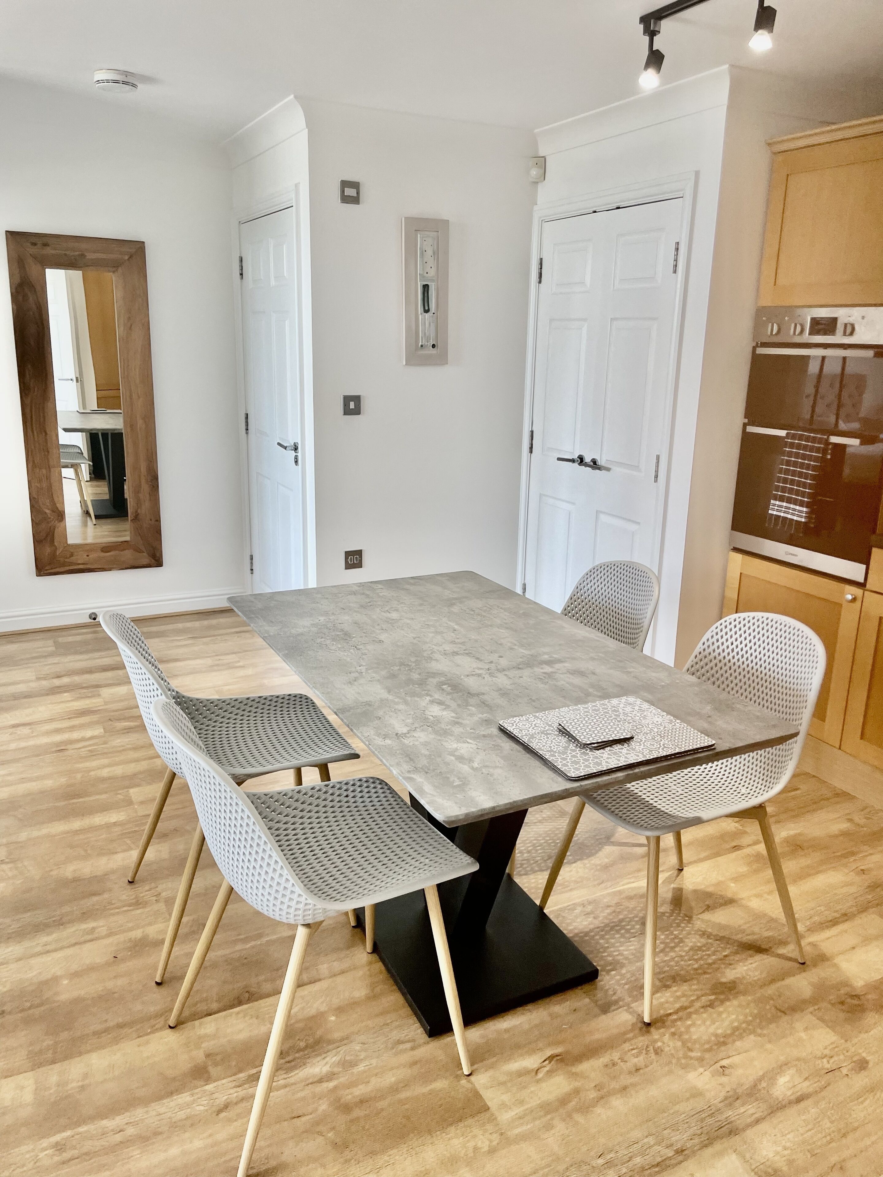 A dining area with a rectangular table, four chairs, and a wooden floor.
