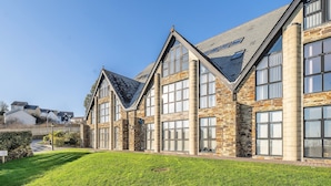 A large building with multiple windows and a sloped roof, surrounded by a well-maintained lawn. - Pochin House Collections (St Austell)