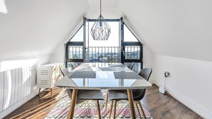 A dining area with a large table, chairs, and a view through a window. - Pochin House Collections (St Austell)
