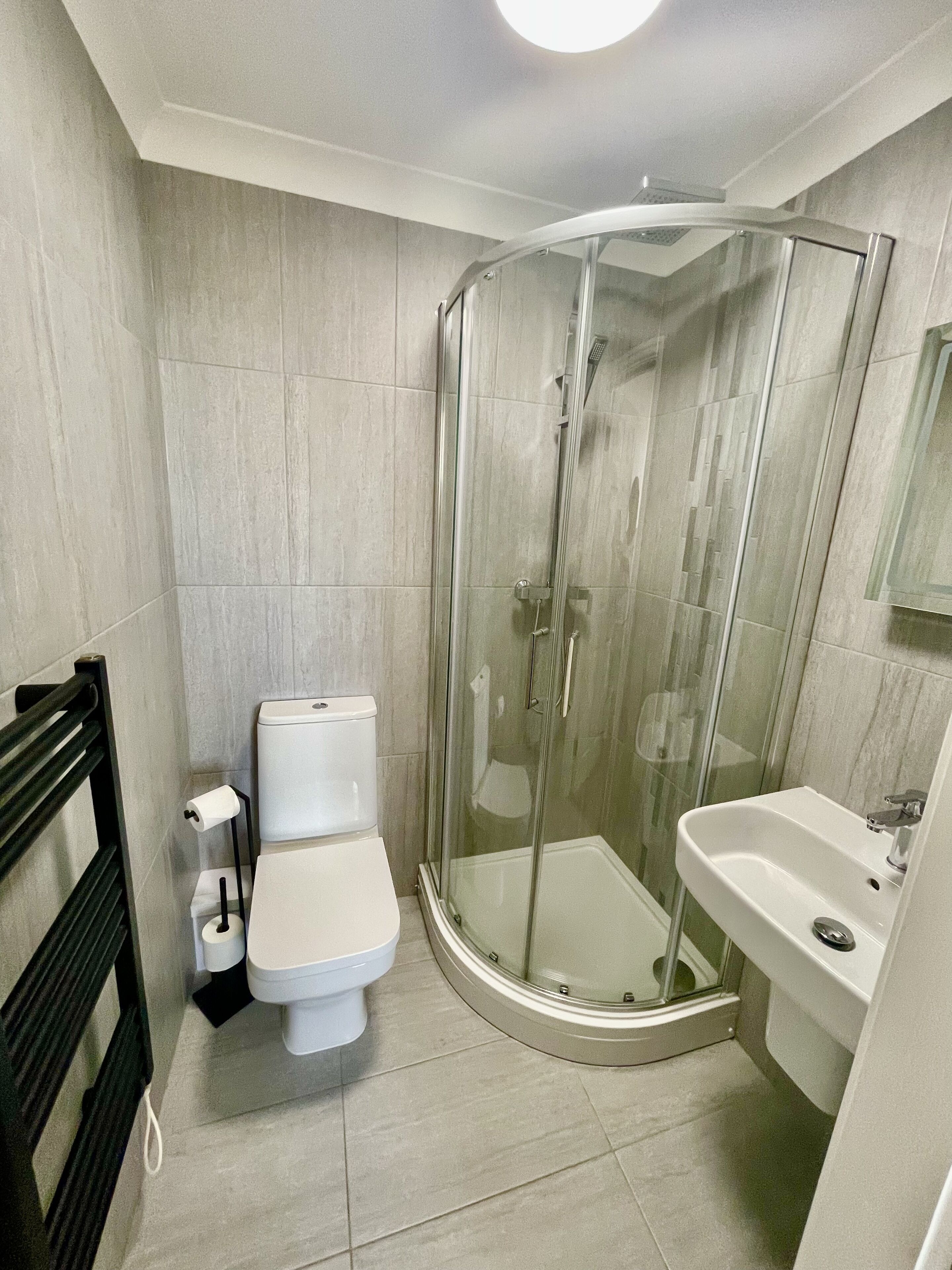 Une salle de bain avec une douche à parois de verre, des toilettes et un lavabo.