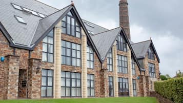A large, multi-story building with a stone facade, large windows, and a prominent chimney.