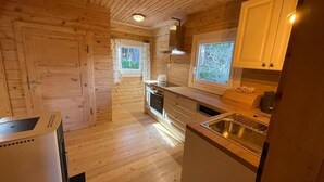 A compact kitchen with wooden walls and a built-in oven. - Waldchalet am Eichhof (Natters)