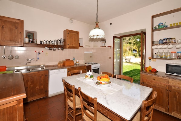 A kitchen with wooden cabinets, a marble countertop, and a view of the outdoors.