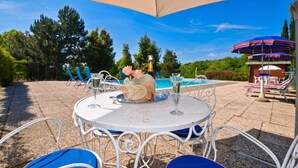 Un patio al aire libre con una mesa redonda, sillas y sombrillas.