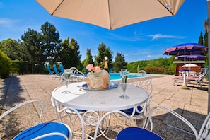 Eine Außenpatio mit einem runden Tisch, Stühlen und Sonnenschirmen.