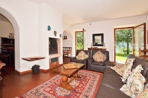 Ein Wohnzimmer mit Kamin, Ledersofa und einem gemusterten Teppich.