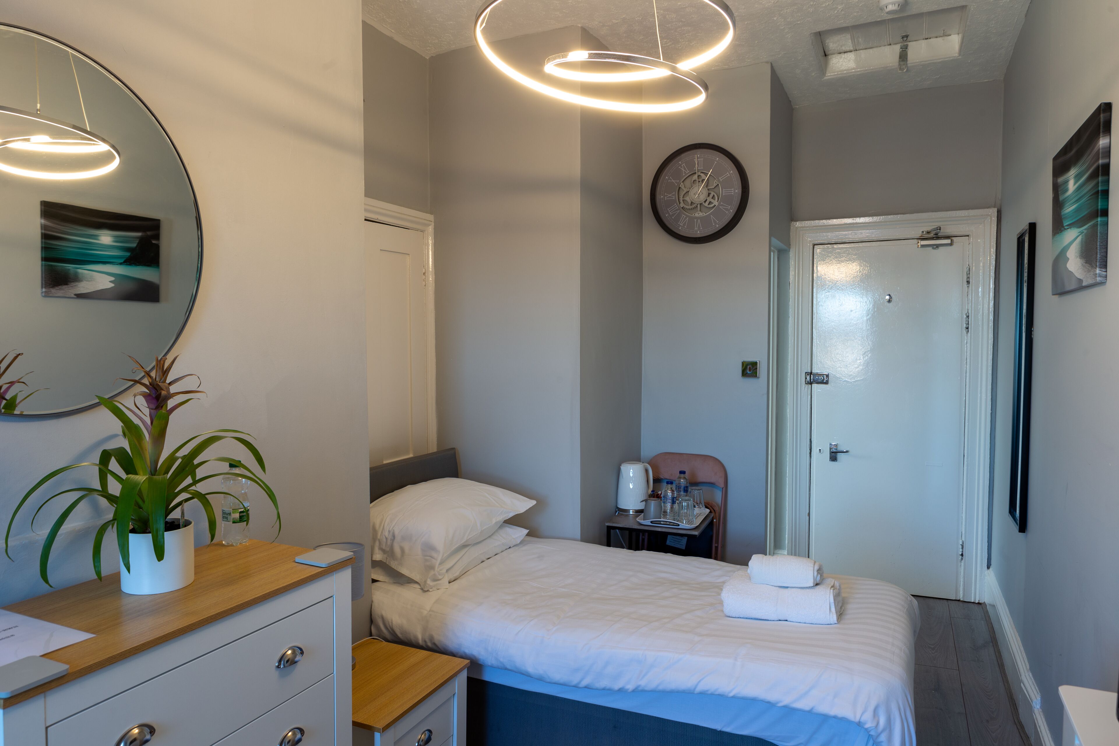 A hotel room with a bed, bedside table, and a desk with drawers.